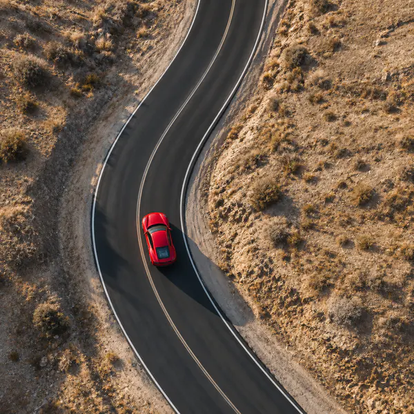 Aerial Drone Shot — A high airborne viewpoint maps the vehicle against roads or terrain, emphasizing route, scale, and graphic patterns